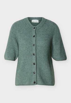 Πράσινη πλεκτή ζακέτα με κοντά μανίκια, στρογγυλή λαιμόκοψη και επτά μαύρα κουμπιά μπροστά.