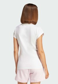 White short-sleeve t-shirt with a round neckline, paired with pink shorts; soft fabric, fitted design, smooth texture.