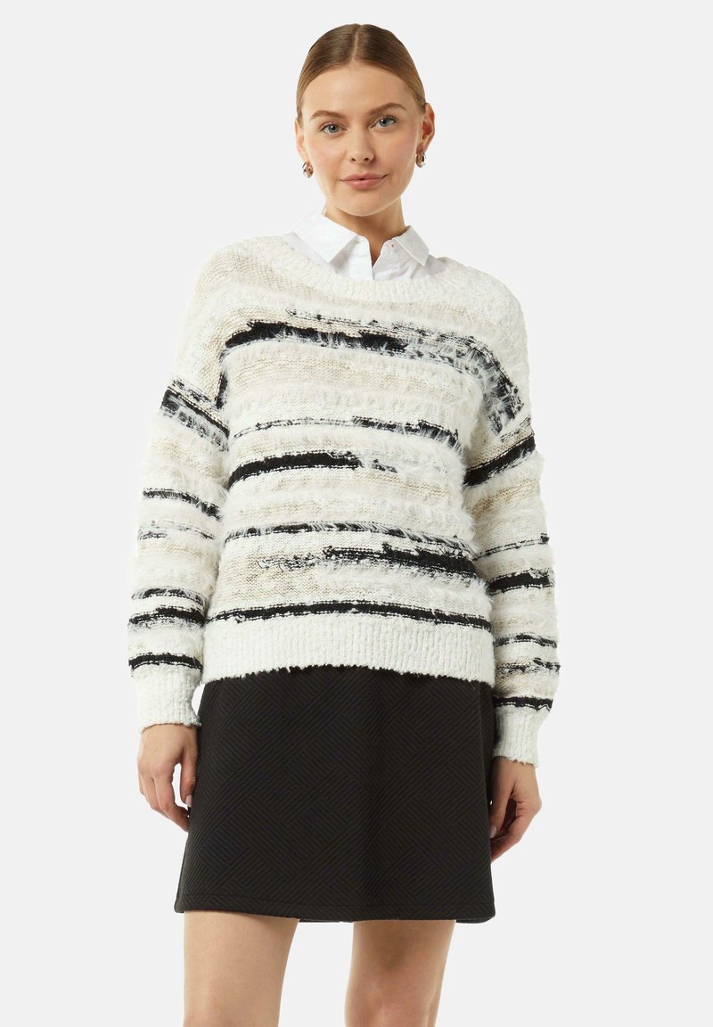 Sweter w paski biało-czarne o teksturowanym wykończeniu, o luźnym kroju i prążkowanym wykończeniu u dołu, zestawiony z czarną spódnicą o teksturowanej powierzchni.