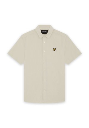 Chemise beige à manches courtes avec col et petit logo d'oiseau jaune et noir sur la poitrine gauche.
