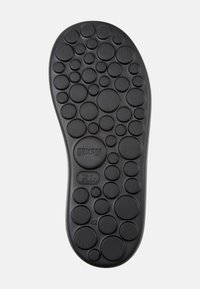 Black rubber shoe sole featuring a circular, textured pattern with varying sizes. Notable branding and size indicators present.