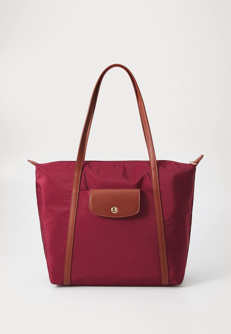 Maroon nylon tote bag with brown leather straps and pocket. Features a gold snap closure on the front pocket. Smooth texture, minimalist design.