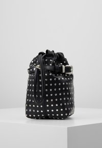 Svart läderväska med metallnitar, cylindrisk form, snörning upptill och justerbar rem. Har silverfärgade detaljer.