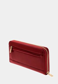Portafoglio rosso con zip e finitura lucida; presenta una tasca esterna e hardware color oro. Forma rettangolare, texture liscia.
