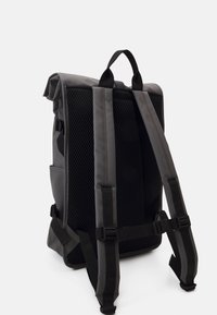 Grå ryggsekk med rull-topp design, mesh bakpanel, justerbare polstrede stropper og svarte detaljer. Har en solid lukking og sidelommer.