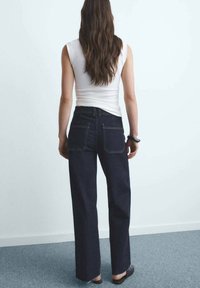 Hoge taille donkerblauwe denim jeans met een rechte pijp, voorzien van vier zakken en contrasterende stiksels. Soepele textuur, minimalistisch ontwerp.