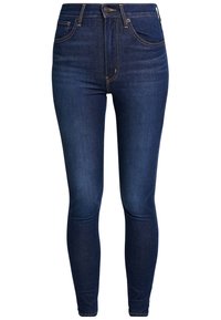 Jeans skinny azul oscuro de denim, con cintura alta, diseño de cinco bolsillos, herrajes en tono dorado y un suave desgaste en toda la prenda.