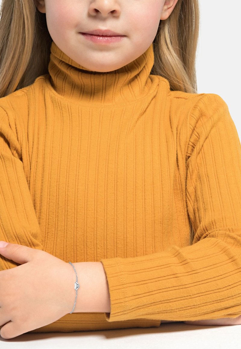 Maglione a collo alto giallo a coste, maniche lunghe. Indossato con un braccialetto argentato con un accento a forma di cuore sul polso di un bambino.