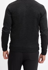 Czarny sweter dziany z długimi rękawami i okrągłym dekoltem. Posiada prążkowany dół i mankiety, wykonany z miękkiego, teksturowanego materiału.