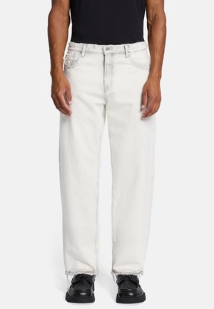 Jeans in denim bianco con una vestibilità ampia, caratterizzati da un orlo sfrangiato e un design tradizionale a cinque tasche. Indossati con scarpe nere e una camicia nera aderente.