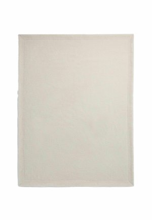 Tapis rectangulaire beige uni avec un motif de bordure discret et une texture douce, posé à plat sur un fond blanc.