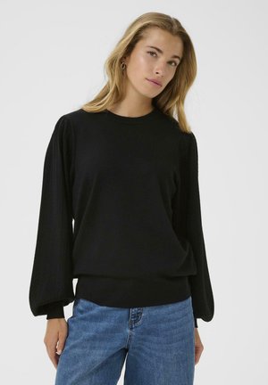 Black knit sweater with textured balloon sleeves, crew neck, and ribbed cuffs. Paired with light blue denim jeans.