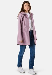 Helllila wasserdichte Jacke mit Kapuze, Reißverschluss auf der Vorderseite und Seitentaschen, kombiniert mit blauen Jeans und weißen Sneakers. Glatte Textur.