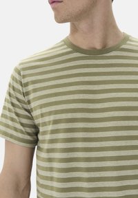Camiseta de rayas verde oliva y blanca, fabricada en suave algodón. Manga corta, escote redondo y diseño minimalista sin gráficos adicionales.