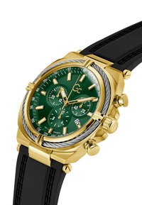 Guld-tonad kronografklocka med en grön urtavla, svart gummirem, suburtavlor för tidsuppföljning och ett datufönster vid 4-o'clock.