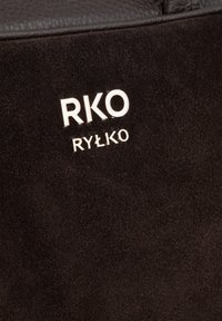 Czarny zamszowy materiał o teksturowanym wykończeniu, z metalicznym logo "RKO RYŁKO" w kolorze srebrnym. Design jest minimalistyczny.