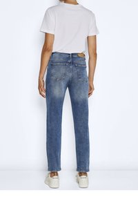 Jeans in denim azzurro chiaro con un taglio dritto, cinque tasche e leggere sbiaditure. Abbinati a una T-shirt bianca e sneakers bianche.