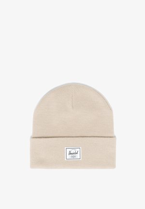 Bonnet tricoté en beige avec un revers. Présente une étiquette de marque blanche cousue à l'avant et un motif en tissu texturé.