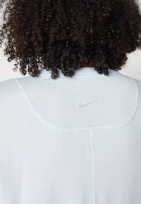 Svijetloplavi atletski top s okruglim izrezom, kratkim rukavima, suptilnim detaljima šivanja i malim sivim Nike logoom na leđima.