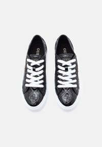 Sneaker in vernice nera con lacci bianchi, caratterizzati da un rivestimento a rombi e un dettaglio con logo di lato. La suola bianca contrasta con la parte superiore.