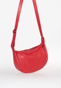 Borsa a tracolla rossa in pelle con design curvo, texture liscia, tracolla regolabile e chiusura con zip.