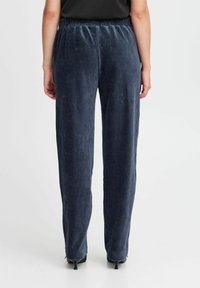 Navy manchesterbyxor med elastisk midja, med vertikal ribbad textur och avslappnad passform. Ankellång med slitsar vid fållen.