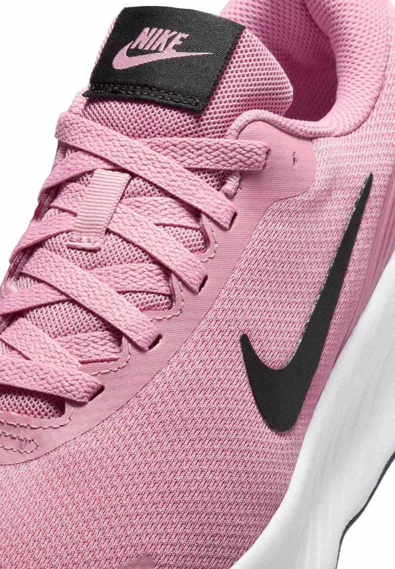 Botte de course Nike rose avec une tige en maille texturée, logo swoosh noir et semelle blanche. Comprend des lacets plats et une languette rembourrée.