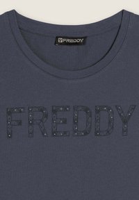 Camiseta de color azul marino oscuro con un cuello redondo y la palabra "FREDDY" en letras texturizadas adornadas con pequeños acentos plateados.
