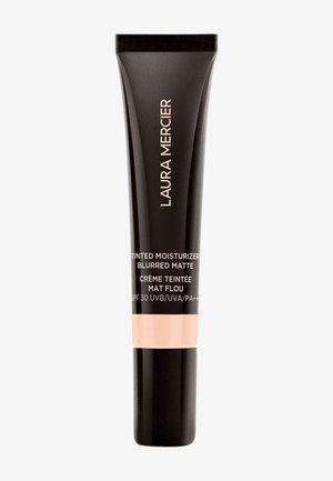 Black tube with matte finish, beige base, and white text. Features "Laura Mercier" logo and product details. SPF 30 indicated.