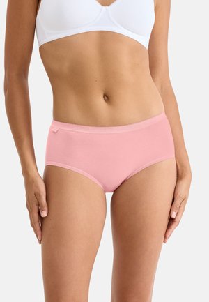Woman wearing plain white bra and light pink cotton hipster underwear against white background.