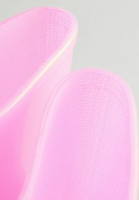 Utensile da cucina in silicone rosa con superficie testurizzata e bordi lisci, caratterizzato da un design senza soluzione di continuità e una forma curva per una facile impugnatura.
