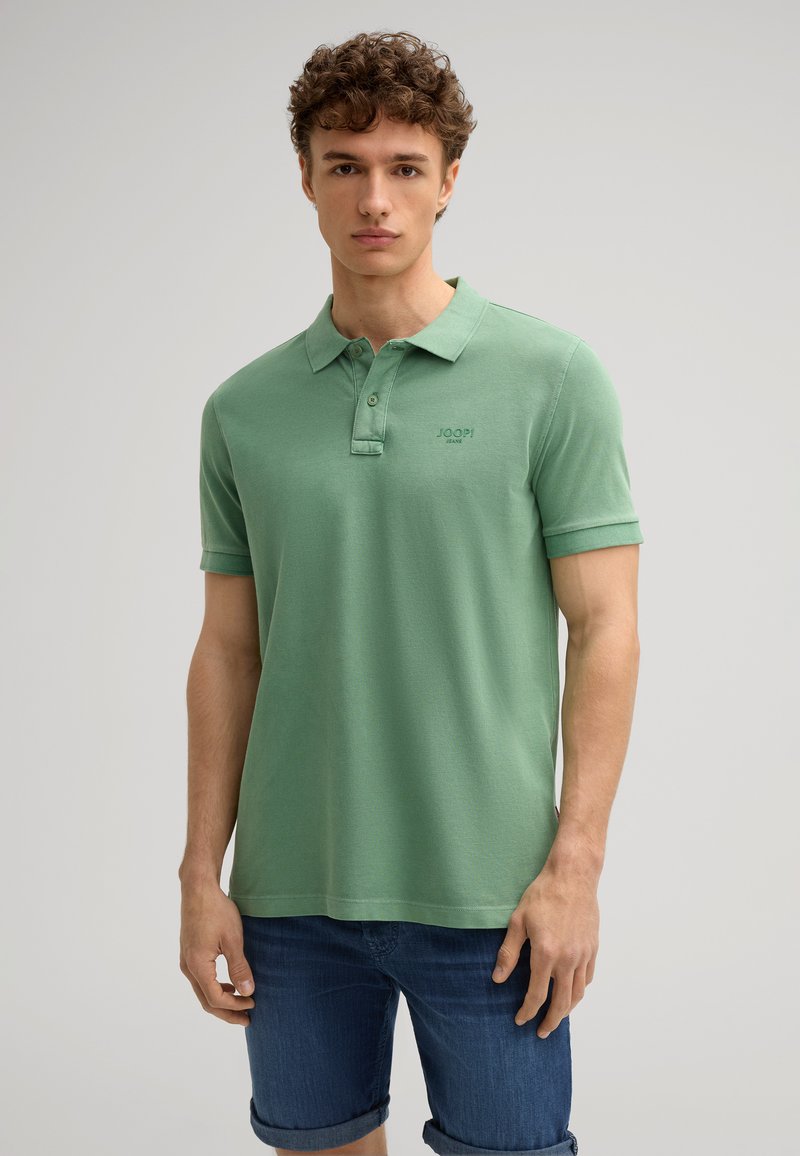Polo shirt in cotone verde con colletto, patta con due bottoni e maniche corte. Presenta un piccolo logo sul petto e una vestibilità comoda.