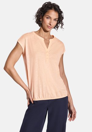 Perzikkleurige T-shirt met korte mouwen en een V-hals, afgewerkt met drie knopen bij de kraag. Heeft een losse pasvorm en een gestructureerde stof.