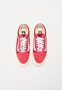 Red suede sneakers featuring white side stripes, white laces, and a cream-colored sole. The design is low-top with a rounded toe.