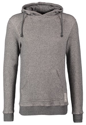 Mand går iført en grå hættetrøje, lyse slidte jeans, sorte støvler og bærer en brun crossbody taske med bred rem.