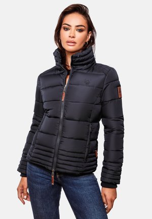 Doudoune noire avec un col haut, design cousu horizontalement et accents en cuir sur les épaules et la fermeture éclair. Portée avec un jean en denim.