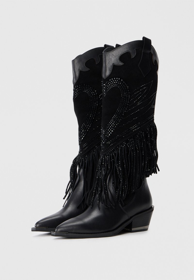 Stivali da cowboy in pelle nera e suede con decorazioni di borchie nere e frange, dotati di punte appuntite e tacchi angolati.