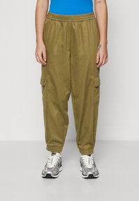 Khaki cargo bukser med elastisk talje, med sidelommer, indsnørede manchetter, parret med sølv- og hvide sneakers.