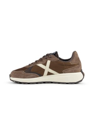 Zapatilla de deporte de ante marrón y beige con suela blanca y cruz blanca cosida en el lateral, vista desde el perfil exterior.