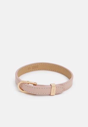 Bracelet en cuir véritable rose clair avec boucle et passant dorés, bords cousus et gravure discrète de la marque sur le passant.