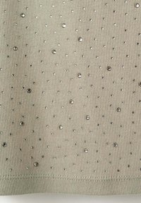 Tissu côtelé brun clair décoré de petits et moyens strass transparents et brillants dispersés.