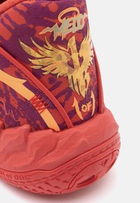 Pomarańczowe i fioletowe sneakersy z teksturowaną gumową podeszwą, wzorzystym materiałem, metalicznymi złotymi grafikami i żywymi akcentami.