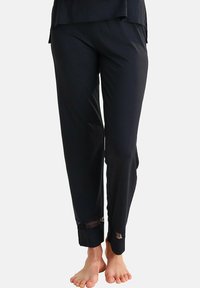 Pantalons noirs avec une texture lisse, ornés de détails en dentelle aux poignets. La taille élastique assure confort et facilité d'enfilage.
