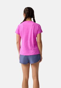 Ružové športové tričko s krátkym rukávom a textúrovaným povrchom, doplnené o modré šortky. Tričko má dizajn s crew neck výstrihom.