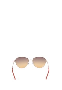 Gafas de sol metálicas con forma de ojo de gato. Lentes marrón degradado, marco plateado delgado y acentos rojos en las puntas de las patillas.