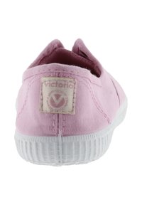 Scarpa slip-on in tela rosa con suola in gomma bianca, dotata di un piccolo etichetta logo sul retro e una superficie in tessuto testurizzato.