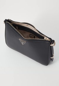 Bolso de mano de cuero sintético negro con herrajes en tono dorado, cierre superior con cremallera y forro interior con un patrón. Presenta un acento con el logo en la parte frontal.