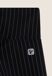 Tela negra con rayas blancas, con un pequeño logotipo gris en la parte inferior derecha. Costuras neat a lo largo de los bordes.