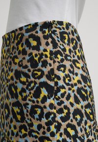 Luipaardprint rok met zwarte, blauwe en gele patronen op een tan achtergrond, voorzien van een zichtbare ritssluiting aan de achterkant.
