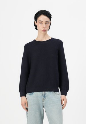 Navy knit sweater with a round neckline, long sleeves, and ribbed hem; paired with light blue jeans in a relaxed fit.